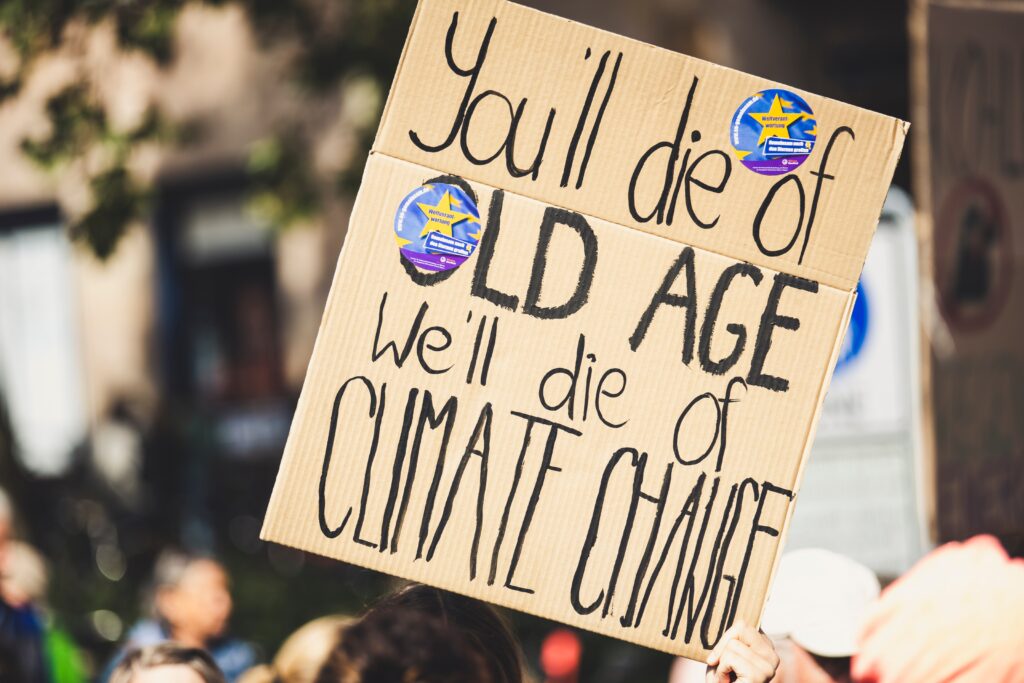 Climate change protest sign that reads "You'll die of old age, we'll die of climate change"